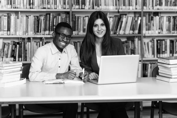 Ζευγάρι των φοιτητών με το Laptop στη βιβλιοθήκη — Φωτογραφία Αρχείου