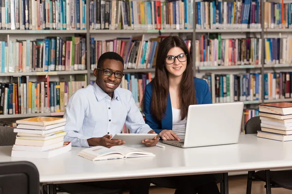 Jovens estudantes usando seu laptop em uma biblioteca — Fotografia de Stock