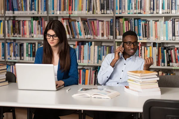 Jóvenes estudiantes usando su computadora portátil en una biblioteca —  Fotos de Stock