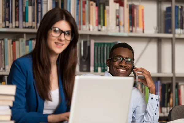 Allievi felici che lavorano con il computer portatile in biblioteca — Foto Stock