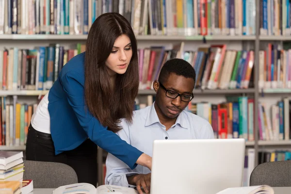 Giovani studenti che utilizzano il loro computer portatile in una biblioteca — Foto Stock