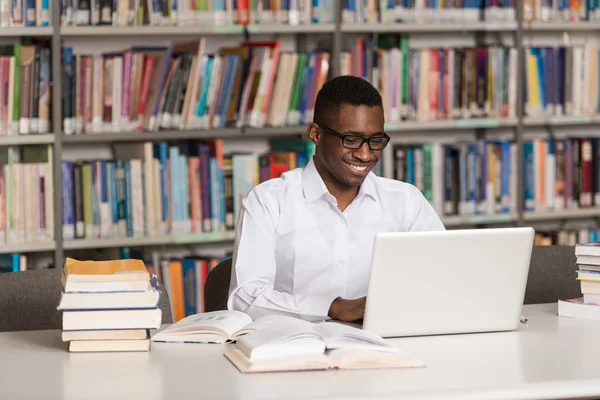 Heureux étudiant africain masculin avec ordinateur portable dans la bibliothèque — Photo