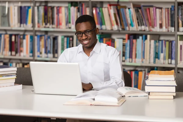Молодий студент використовує свій ноутбук в бібліотеці — стокове фото