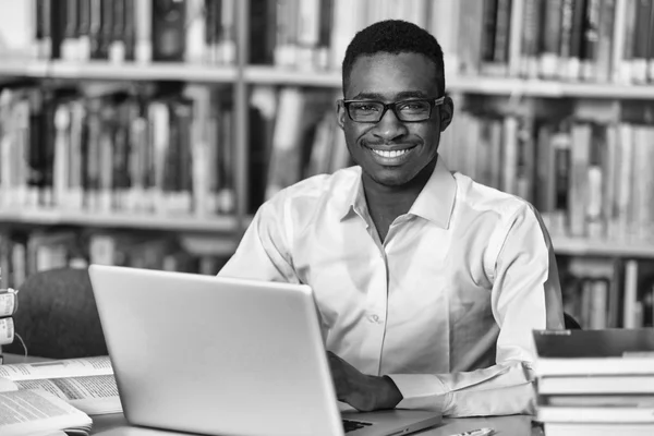 Estudiante africano feliz con el ordenador portátil en la biblioteca — Foto de Stock