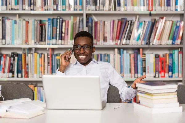 Homme étudiant parler au téléphone dans la bibliothèque — Photo