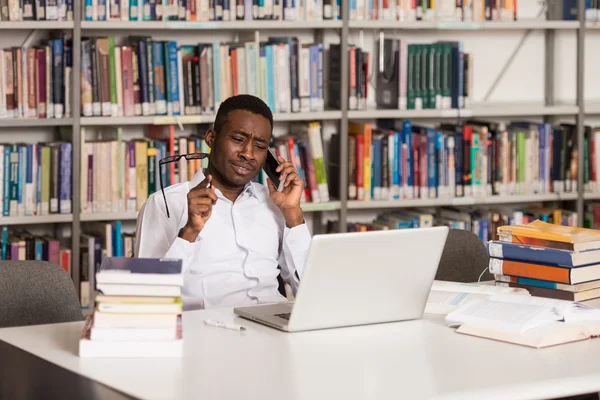 Studentowi rozmawia przez telefon w bibliotece — Zdjęcie stockowe