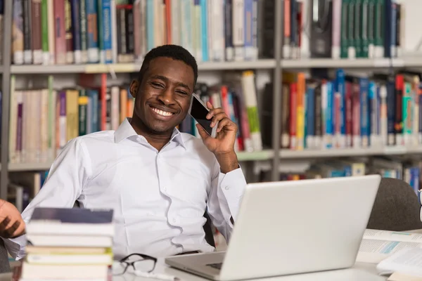 Estudante masculino conversando ao telefone na biblioteca — Fotografia de Stock