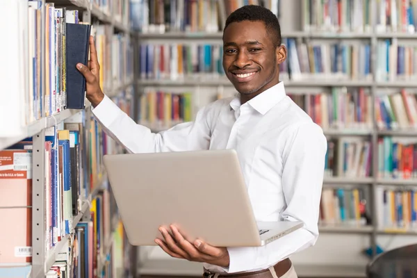 Szczęśliwy studentowi z laptopa w bibliotece — Zdjęcie stockowe