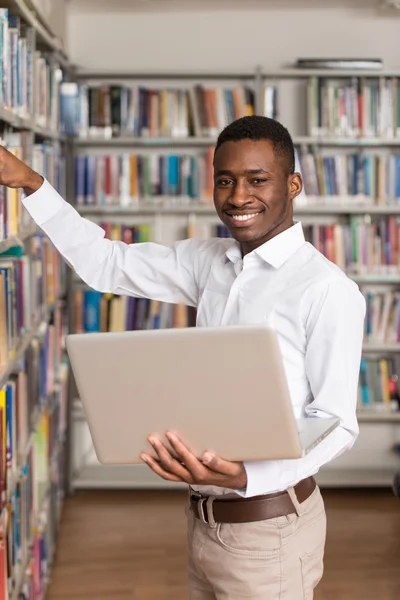 Ung Student med sin Laptop i ett bibliotek — Stockfoto