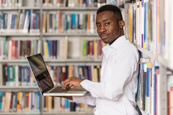 Szczęśliwy studentowi z laptopa w bibliotece — Zdjęcie stockowe