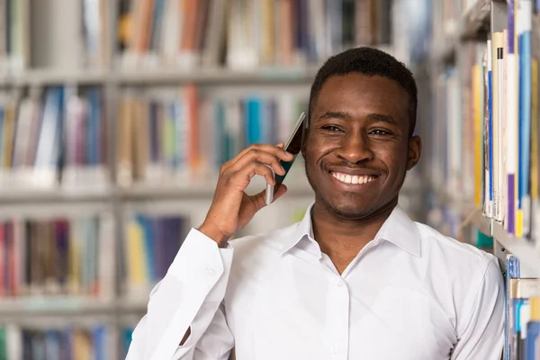 Estudante masculino conversando ao telefone na biblioteca — Fotografia de Stock