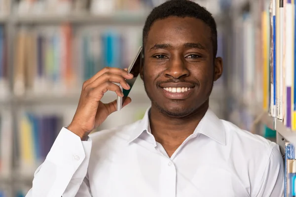 Férfi diák, beszél a telefonon, a könyvtár — Stock Fotó