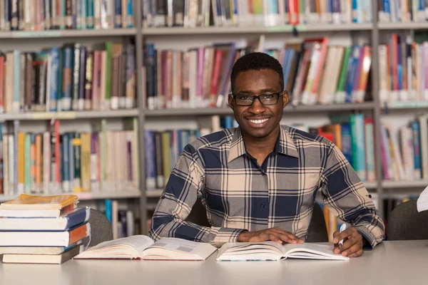 Jeune étudiant assis à la bibliothèque — Photo