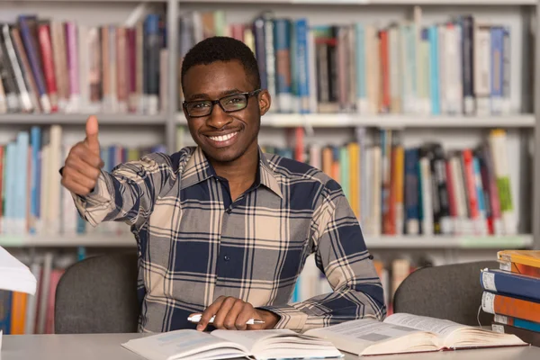 Afrykański mężczyzna w bibliotece wyświetlane kciuki — Zdjęcie stockowe