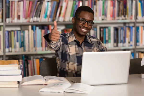 Homem africano em uma biblioteca mostrando polegares para cima — Fotografia de Stock