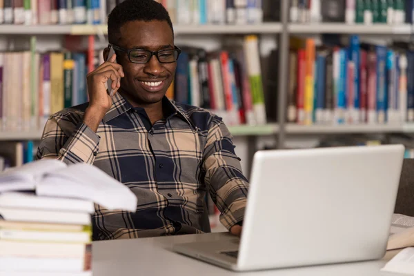 Estudante masculino conversando ao telefone na biblioteca — Fotografia de Stock