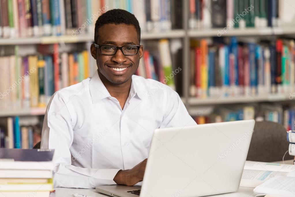 Young Student Using His Laptop In A Library