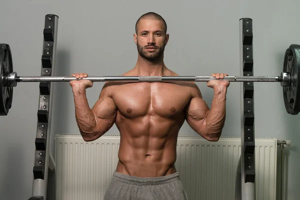 Bodybuilder uitoefening schouders met Barbell — Stockfoto