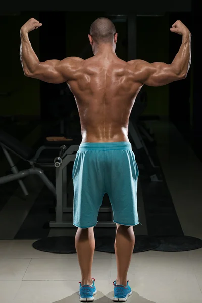 Bonne forme physique homme effectuant arrière pose doubles biceps — Photo