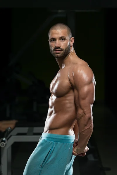 Muž v tělocvičně ukazující jeho dobře vyškolených tělo — Stock fotografie