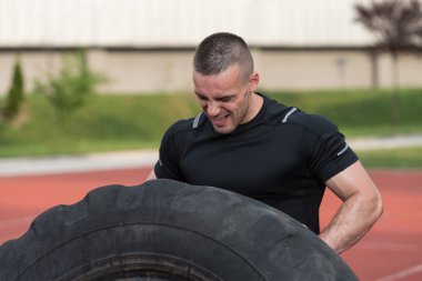 Young Man Doing Tire Flip Workout Outdoor