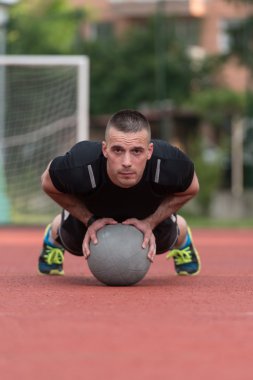 Young Man Exercising Push-Ups On Medicine Ball Outdoor