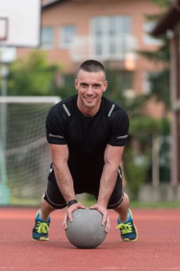 Young Man Exercising Push-Ups On Medicine Ball Outdoor