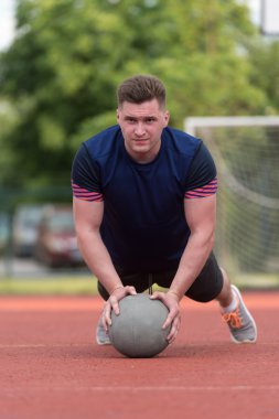 Young Man Exercising Push-Ups On Medicine Ball Outdoor