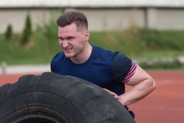 Young Man Doing Tire Flip Workout Outdoor