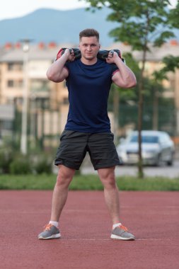 Young Man Doing Bag Squat Exercise Outdoor