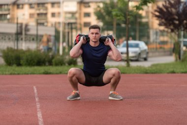 Young Man Doing Bag Squat Exercise Outdoor