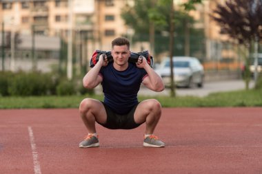 Young Man Doing Bag Squat Exercise Outdoor