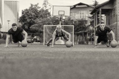 Group Of People Exercising Push-Ups On Medicine Ball