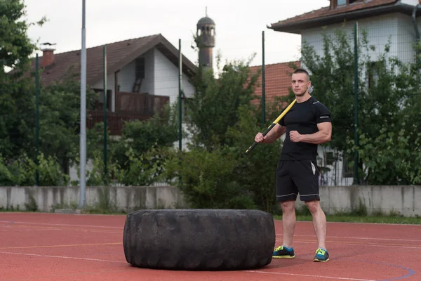 Young Man Hits Tire With Hammer Outdoor — Zdjęcie stockowe