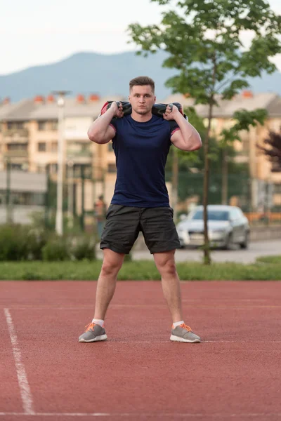 Young Man Doing Bag Squat Exercise Outdoor — Stock fotografie