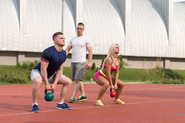 Two People Doing Kettlebell Exercise Outdoor With Instructor — Stok fotoğraf