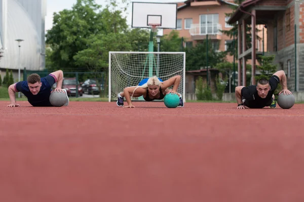 Group Of People Exercising Push-Ups On Medicine Ball — Stok fotoğraf