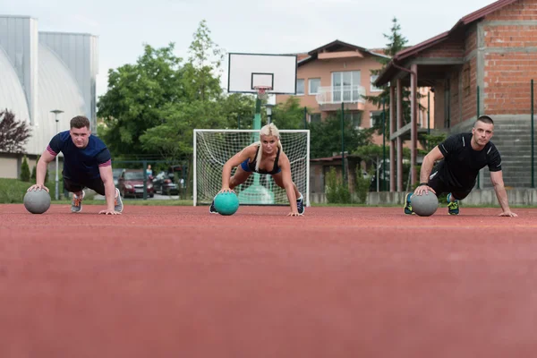 Gruppo di persone che esercitano push-up sulla palla della medicina — Foto Stock