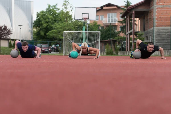 Grupo de pessoas que exercem Push-Ups na bola de medicina — Fotografia de Stock