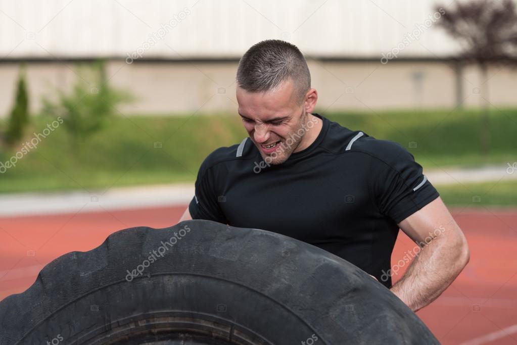 Young Man Doing Tire Flip Workout Outdoor