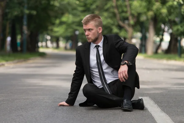 Moe zakenman zittend op asfalt buitenshuis In Park — Stockfoto