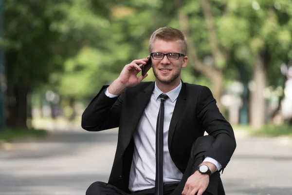 Młody biznesmen w telefonie na świeżym powietrzu w parku — Zdjęcie stockowe