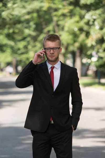 Businessman Walking Outside In Park While Using Mobilephone — Stock Photo, Image