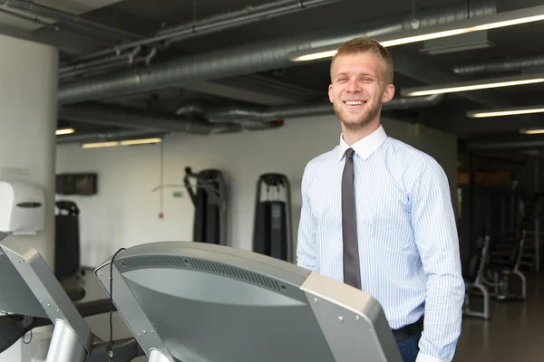 Homme d'affaires courant sur tapis roulant dans la salle de gym — Photo