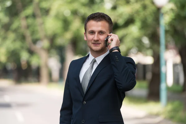 Mladý podnikatel na telefonu venku v parku — Stock fotografie