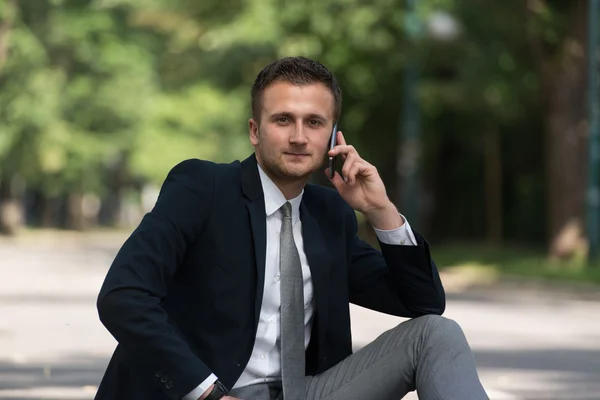 Ung affärsman på telefonen utomhus i parken — Stockfoto