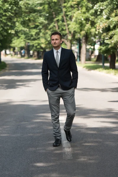 Jovem homem de negócios caminhando ao ar livre no parque — Fotografia de Stock