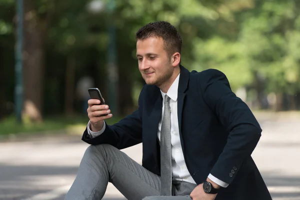 Ung affärsman på telefonen utomhus i parken — Stockfoto