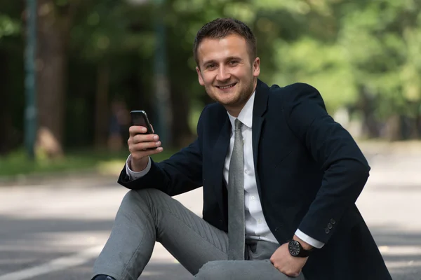 Ung affärsman på telefonen utomhus i parken — Stockfoto