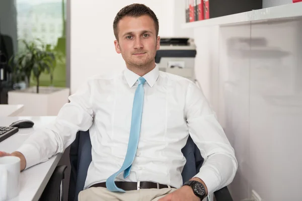 Jovem empresário relaxa sentado no escritório — Fotografia de Stock